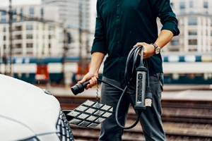 Man Holding Juice Cable Next to Car