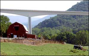 Bridge spanning a valley with a farm with a red barn in the foreground