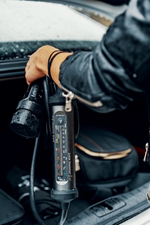Man Putting Juice Cable in Trunk of Car